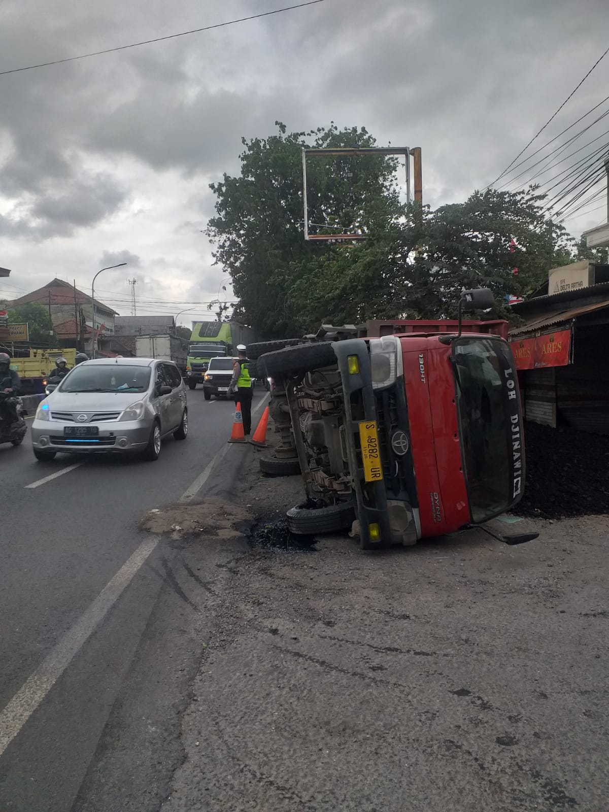 Baut ban belakang lepas, dump truk muat batu bara terguling menimpa bengkel sepeda motor